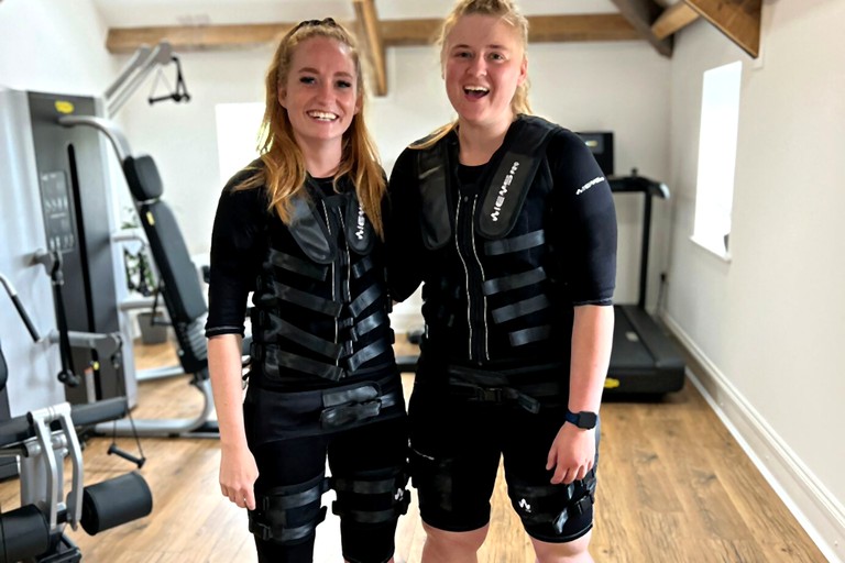 Two EMS clients smiling inside fitness studio