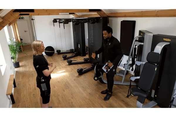 Coach guiding client through EMS exercise with attentive posture