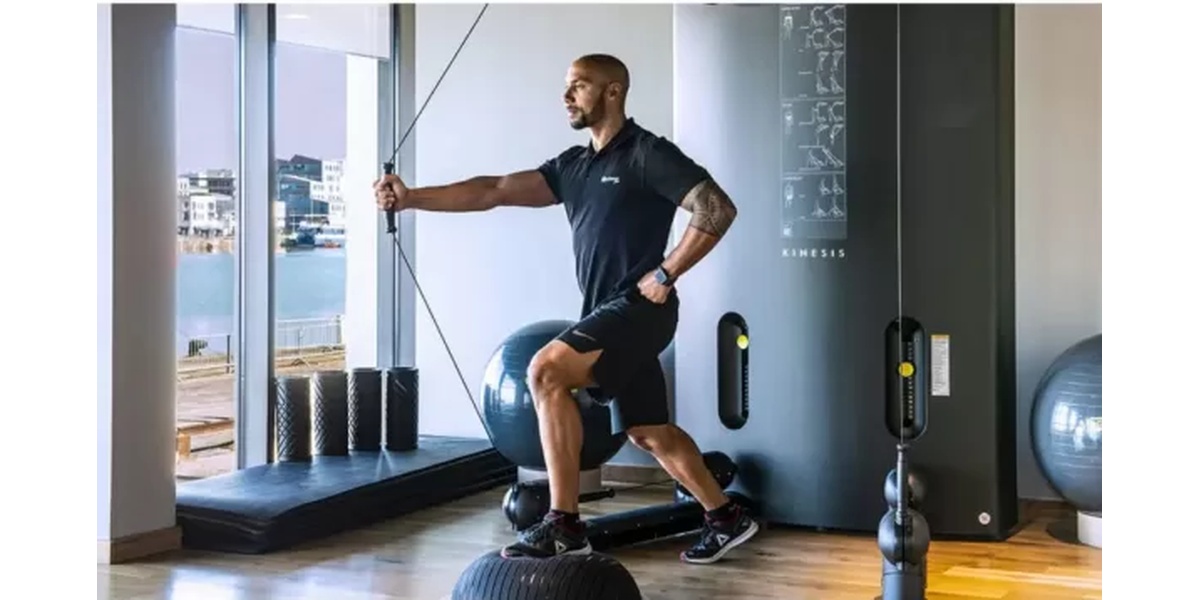 Client wearing EMS suit training with coach in modern studio with warm lighting